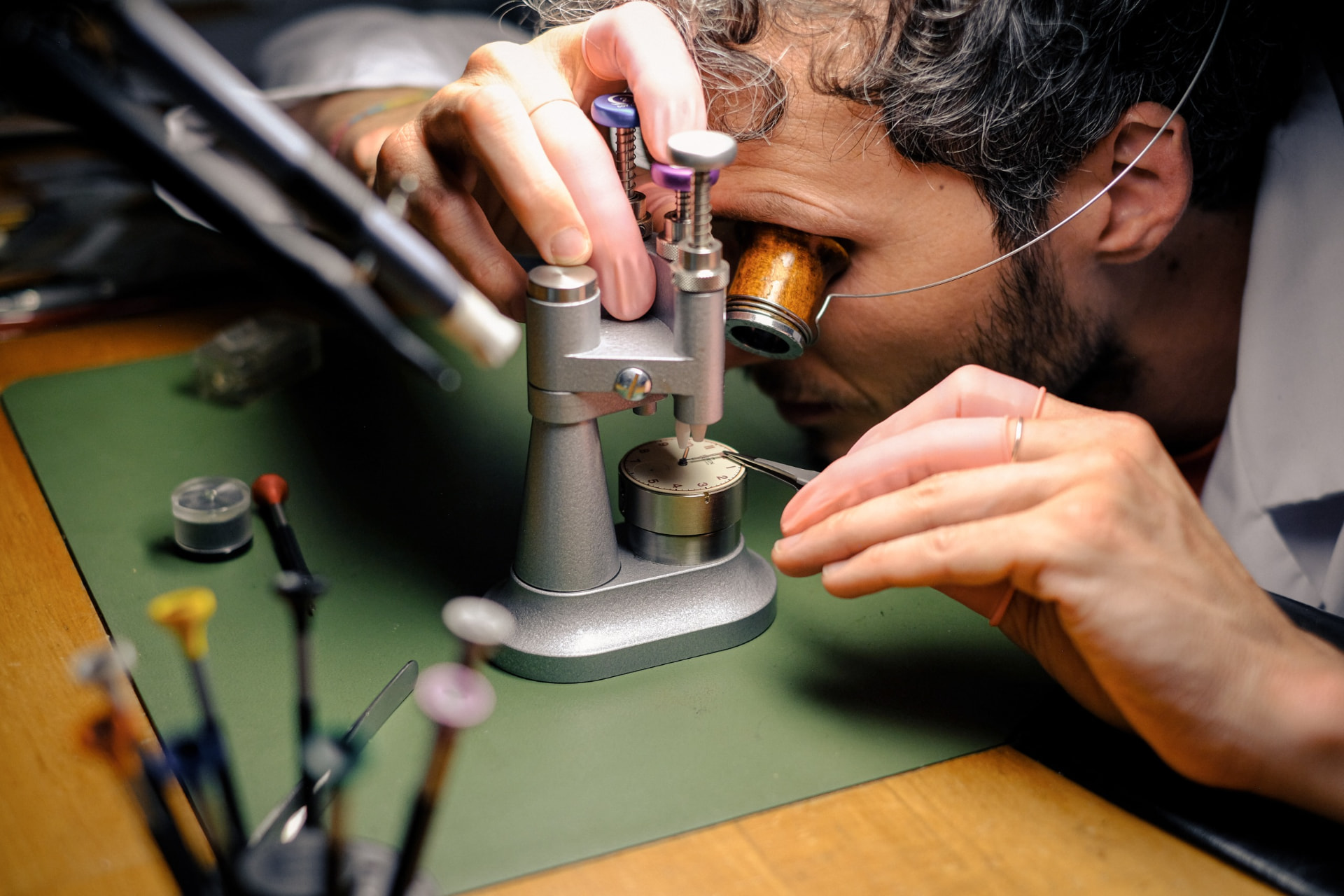 Watchmaker with a loupe adjusting a movement on a timing tool